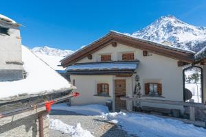 a house in the snow with a mountain in the background at Chesa Cavril in Maloja +8 photos