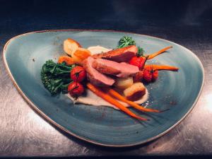 a blue plate with carrots and vegetables on a table at The Boathouse in Rollesby +3 photos