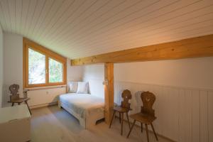 a bedroom with a bed and two chairs and a window at Chesa Maria 7 in Sils Maria