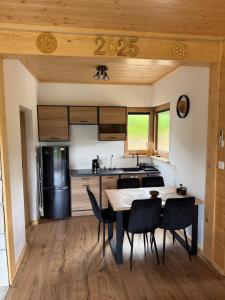 a kitchen with a table and chairs and a refrigerator at Marcinówka - Górski Domek w Gorcach in Tylmanowa