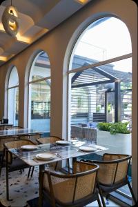 a dining room with tables and chairs and windows at Basilica Resort, Lonavala in Lonavala