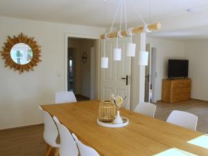 a dining room with a wooden table and white chairs at Hof Muhs in Stakendorf
