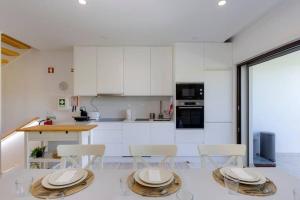 a kitchen with white cabinets and white tables and chairs at Morada do Sol with Private Pool & Garden in Alvor