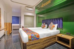 a bedroom with a large bed with a green wall at FabHotel Dukes Plaza in Ulhāsnagar