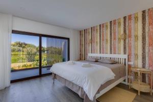 a bedroom with a large bed and a large window at Morada do Sol with Private Pool & Garden in Alvor