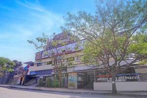 a building on the side of a street with a tree at FabHotel Dukes Plaza in Ulhāsnagar