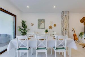 a white dining room with a white table and chairs at Morada do Sol with Private Pool & Garden in Alvor