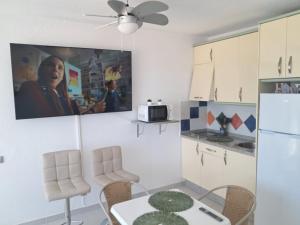 a kitchen with a table and a white refrigerator at Apartahotel Estudio 221 in Matalascañas