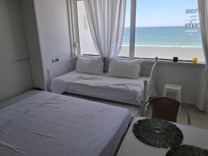 two beds in a room with a view of the ocean at Apartahotel Estudio 221 in Matalascañas