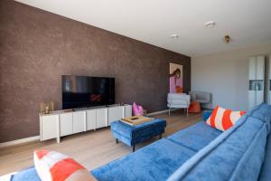a living room with a blue couch and a tv at Oan 'e Haven in Oudega