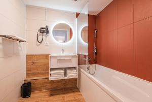 a bathroom with a tub and a sink and a mirror at Residhotel Mulhouse Centre in Mulhouse +26 photos