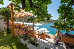 a restaurant with tables and umbrellas next to a body of water at Cako Rooms Saranda in Sarandë