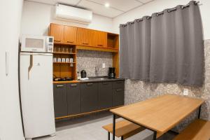 a kitchen with a refrigerator and a wooden table at VILLA BILAC - Large Studios close to Vila Germânica in Blumenau
