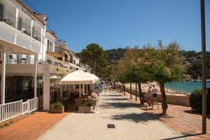 a sidewalk next to a beach with people sitting on benches at Hostal La Llagosta in Llafranc