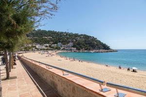 a beach with people on the sand and the ocean at Hostal La Llagosta in Llafranc