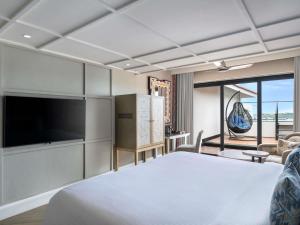 a bedroom with a bed and a flat screen tv at Grand Mercure Goa Candolim - An Accor Hotels Brand in Candolim +182 photos