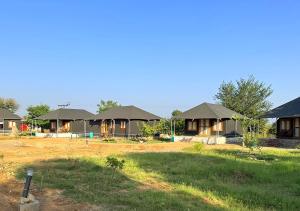 a row of lodges with roofs in a field at Thour Nature Resorts Jawai in Bera