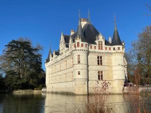 a castle sitting in the middle of the water at La maison du pont du gué in Bourgueil
