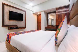 a hotel room with a bed and a tv at FabHotel Prasad International in Mumbai