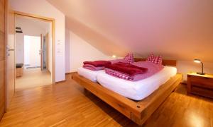 a bedroom with a bed with red pillows on it at Ferienwohnungen beim Sommermader - inklusive Königscard in Nesselwang +34 photos