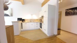 a kitchen with white cabinets and a white wall at Ferienwohnungen beim Sommermader - inklusive Königscard in Nesselwang