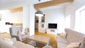 a living room with white furniture and a tv at Ferienwohnungen beim Sommermader - inklusive Königscard in Nesselwang