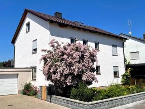 a white house with a flowering tree in front of it at FerienNest Kelheim in Kelheim