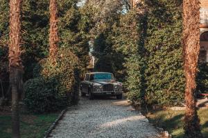 an old car parked on a gravel road between trees at Villa Evelina in Travedona