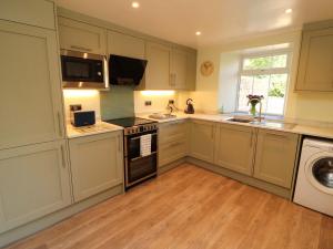a kitchen with white cabinets and a stove top oven at East View in Kirkby Stephen