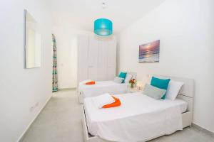 a white room with two beds and a couch at Hillock Residence Marsalforn in Marsalforn +14 photos