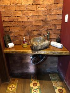 a bathroom counter with a sink and a brick wall at Chalé das Flores in Brumadinho