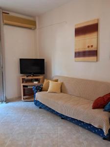 a living room with a couch and a flat screen tv at Evgenias Beach Escape in Kallithea Halkidikis