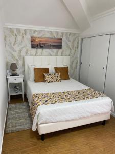 a bedroom with a large white bed and a night stand at Moradia Ricardo - Nazaré in Nazaré