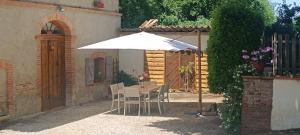 a table and chairs under an umbrella in a yard at Le moulin de Christine in Saint-Nauphary