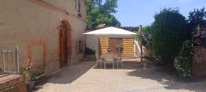 a patio with an umbrella and a table and chairs at Le moulin de Christine in Saint-Nauphary