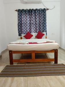 a bed with red pillows on it in a room at Ojasvi Experience in Morjim