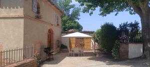 a patio with a table and an umbrella next to a building at Le moulin de Christine in Saint-Nauphary