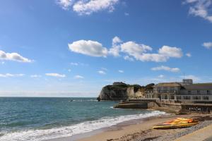 a beach with a building and a boat on the shore at 8 Manor Villas in Totland