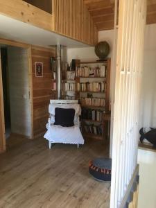 a room with a white chair and a book shelf at Maison La Voyageuse in Gorses