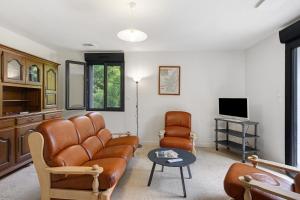 a living room with a leather couch and a tv at La Clémenguite in Vals-les-Bains