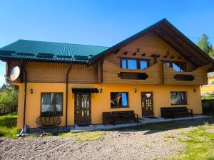 a house with a green roof with two benches at Приватна садиба "Гереджука" in Vorokhta