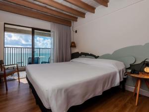 a bedroom with a large white bed and a balcony at Ibis Styles Maragogi in Maragogi