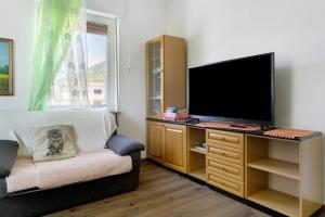 a living room with a desk with a tv and a chair at Casa Rosa in Levico Terme