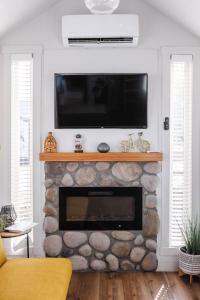 a living room with a fireplace with a flat screen tv above it at Near Zion Modern Tiny Home Hiking & MTB Access in Apple Valley