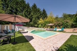 a swimming pool with an umbrella and chairs and a table with an umbrella at Domaine des légendes in Plumelin