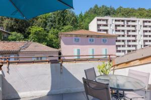 a table and chairs on a balcony with a building at Élégant T3 Terrasse & Wifi in Vals-les-Bains