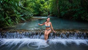 a woman in a bikini standing on a waterfall at Ecocio Explorations in Coron