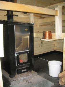 a woodburning stove in a kitchen with a bucket at Kuulapää Chalet in Äkäslompolo