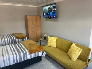 a living room with a couch and a tv on the wall at Abijah Ridgeview Studios in Roodepoort