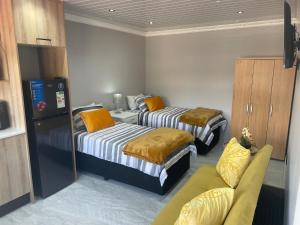 two beds in a small room with a couch at Abijah Ridgeview Studios in Roodepoort